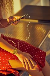 anonymous woman sitting on metal bench with earphones and smartphone