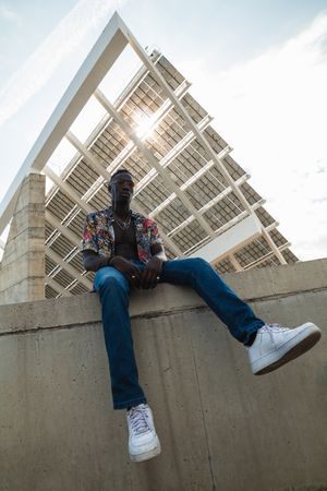 Hipster man in trendy outfit sitting on fence