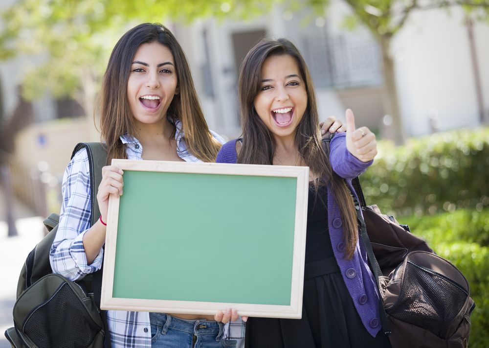 Female Students with Thumbs Up Holding Blank Chalkboard