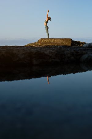 Woman performing yoga near sea water