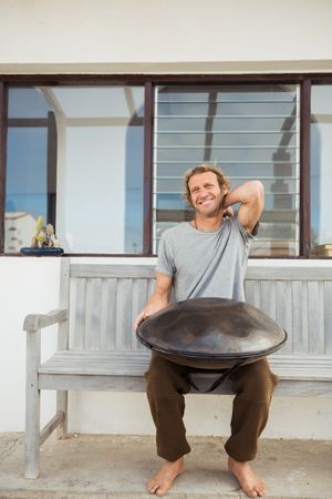 Blond man sitting on bench with big hand drum