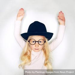 Serious blonde girl with arms up in hat and glasses 0vo7g5
