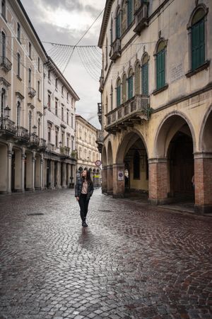 Curious female tourist strolling at old city street on overcast weather