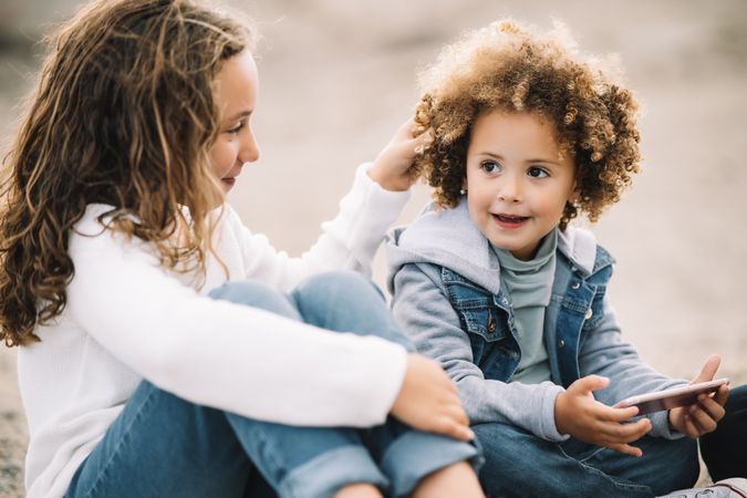 Cheerful kids interacting on nature with smartphone