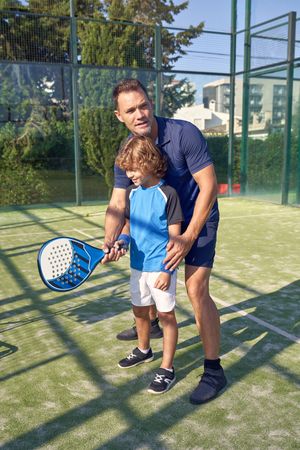 Coach and boy exercising with racket