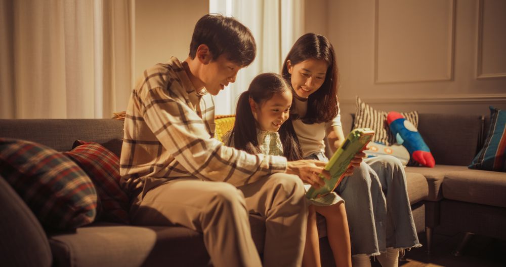 Portrait of Happy Korean Family Using Digital Tablet Computer While Sitting in the Living Room.