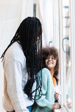 Black father with daughter standing near window