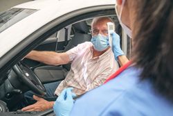 Crop nurse measuring temperature of driver with infrared thermom