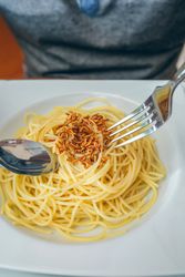Hands of man eating spaghetti with worms