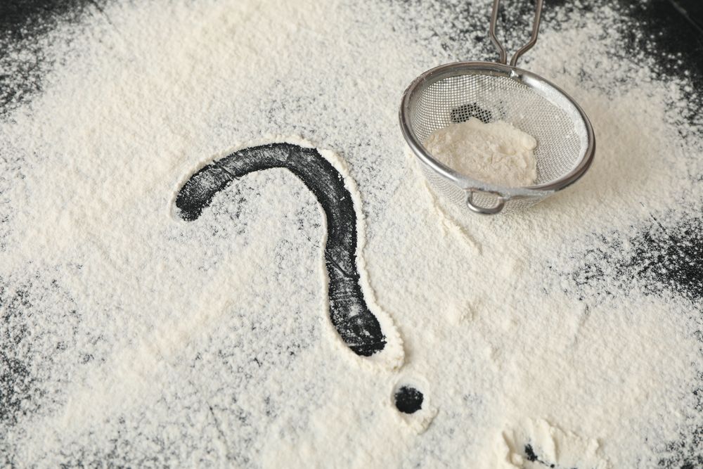 Flour, sieve and question mark on dark background