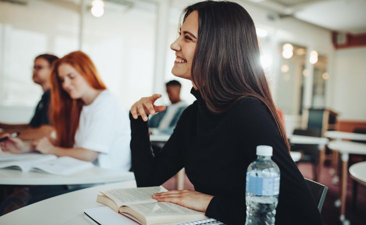 Woman with brown hair smiling at professor during class discussion