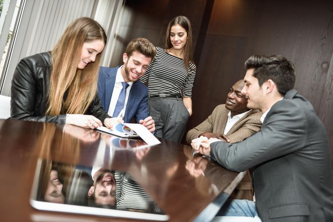 Male and female co-workers working on charts and graphs in a meeting room