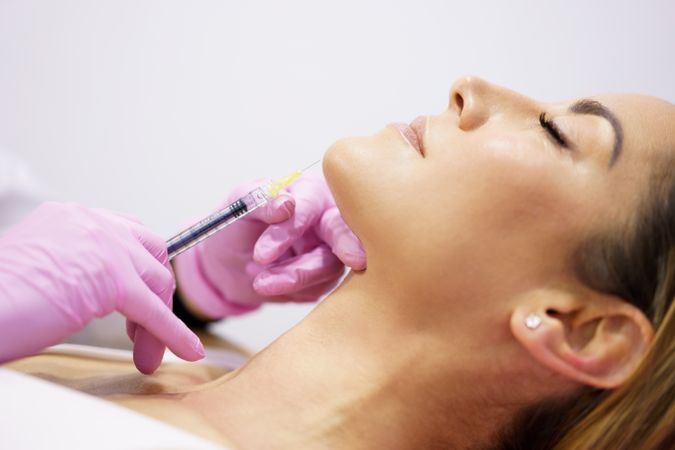 Woman having fillers injected into jawline