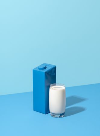 Glass of milk and carton milk box isolated on a blue background