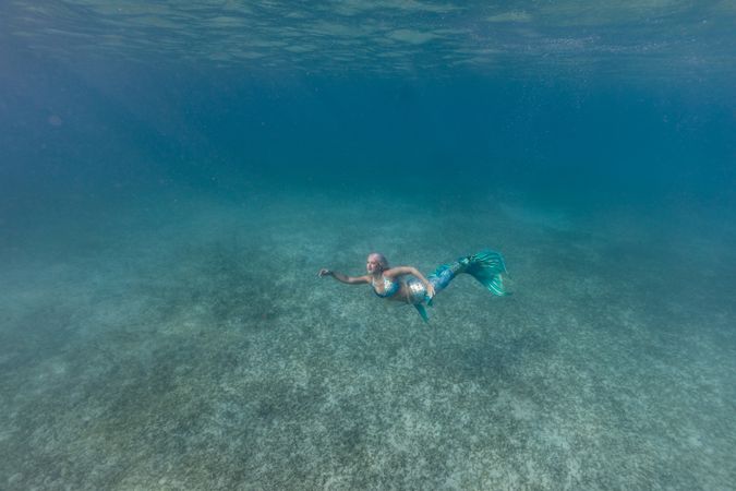 Blond fairytale female mermaid swimming underwater