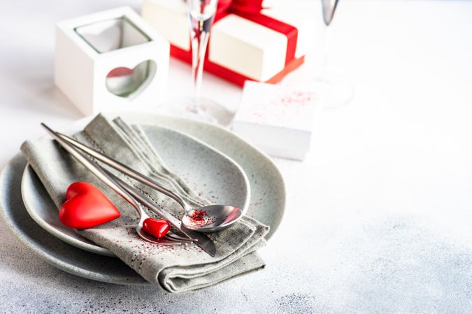 Valentine Day holiday card concept with grey table setting with red hearts and glitter