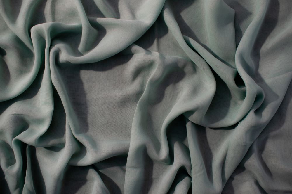 Nude green fabric wavy crumpled background texture with copy space.