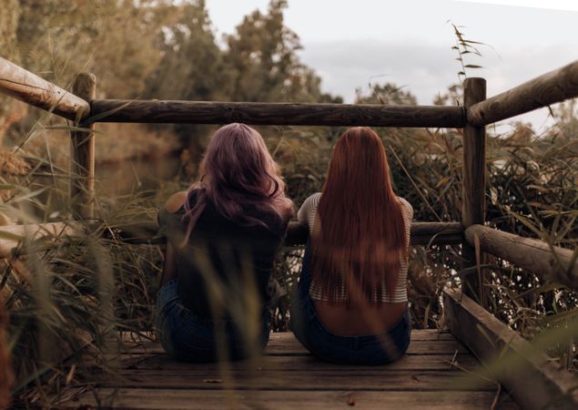 Women sitting on wooden pier in nature