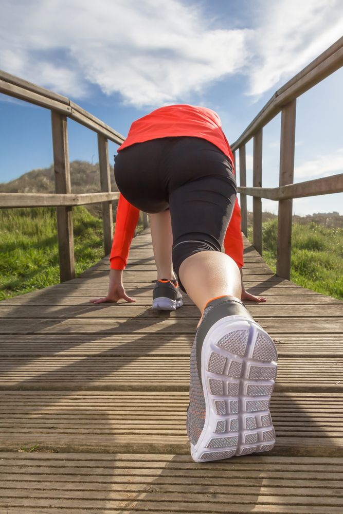 Back of woman ready to sprint down wooden path
