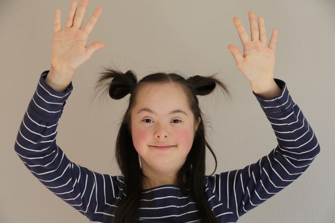 Portrait of an adorable child raising her arms up