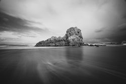 Coastal rock on beach and overcast sky