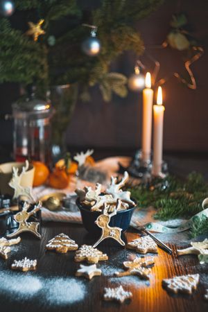 Winter Christmas cookies on dark table with candles and greenery