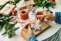 Anonymous person tying Christmas gift box on decorated table