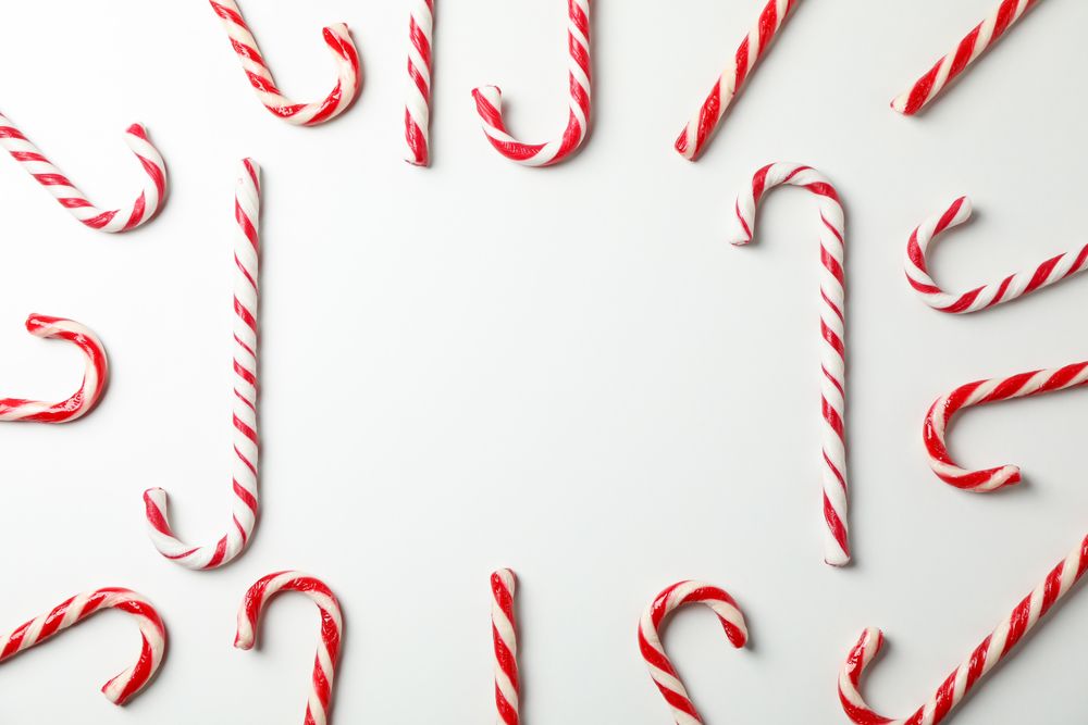 Composition with sweet candy canes on plain background, space for text
