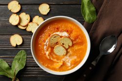 Top view of bowl of delicious pumpkin soup on wooden table