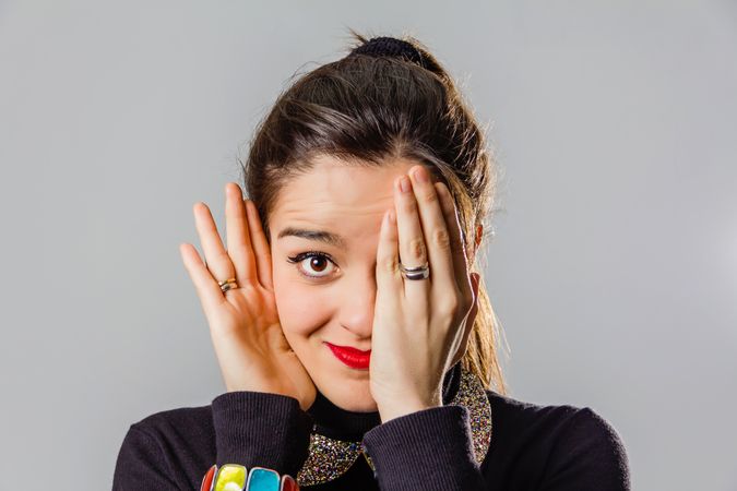 Woman with red lips using her hand to cover one eye