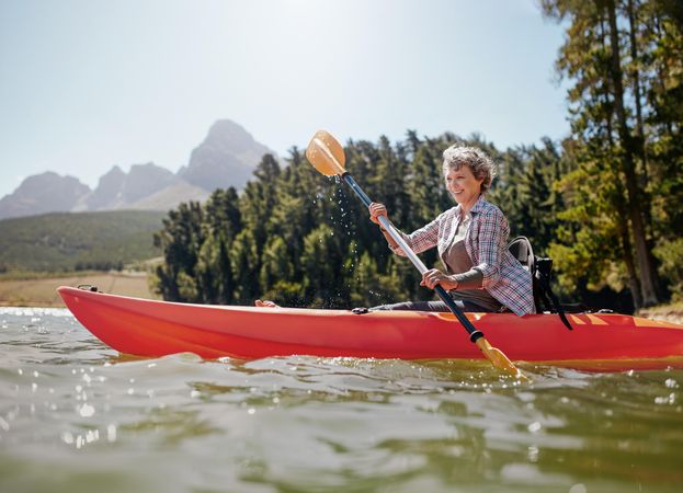 Shot of odler woman kayaking on lake on a summer day