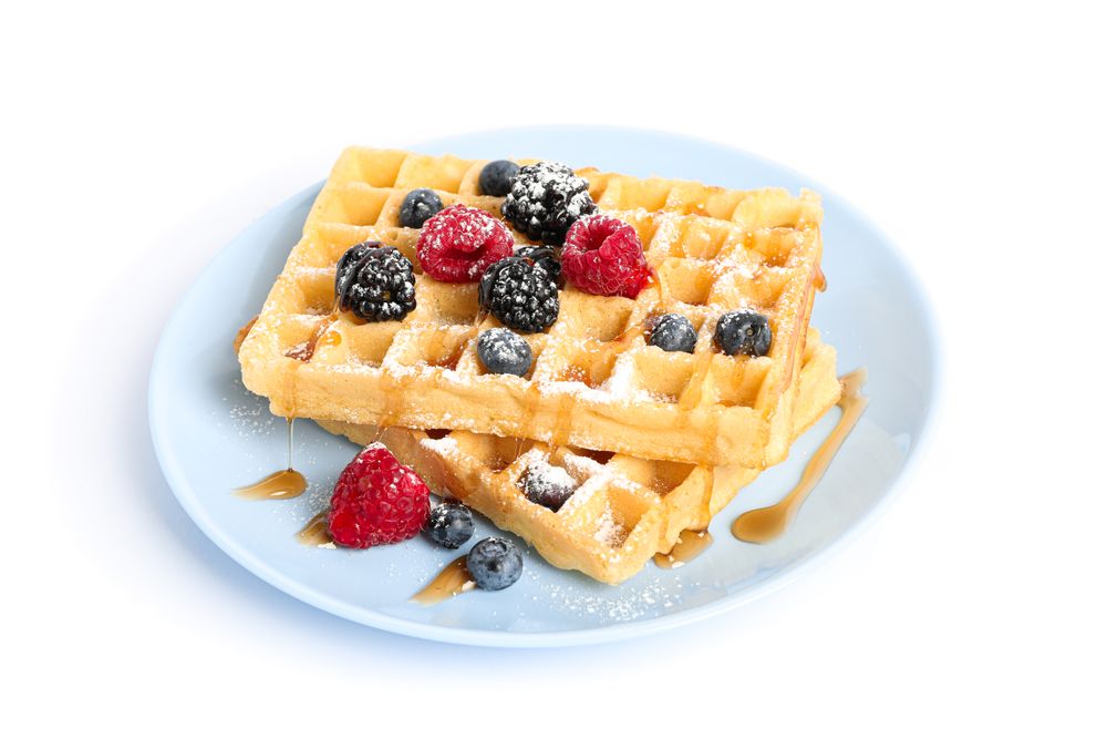 Waffles with berries on plate isolated on blank background
