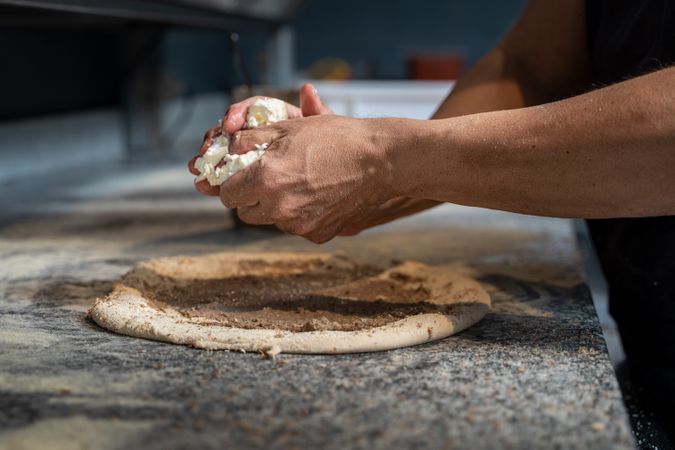 Professional pizza chef preparing dough with fresh mozzarella