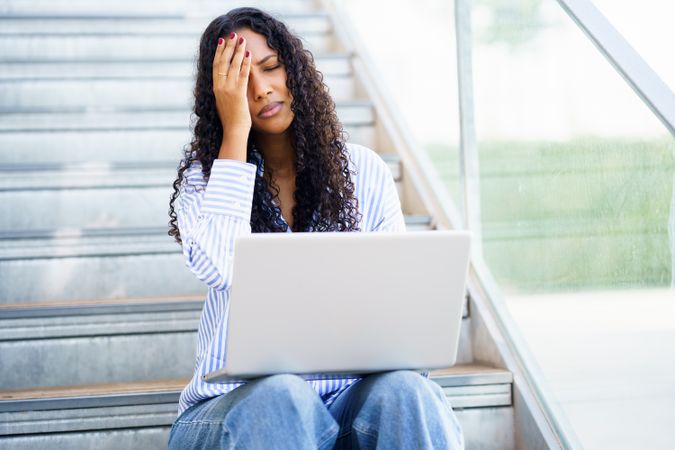 A Stressed Woman Working on Her Laptop While Sitting on the Stairs She Feels Overwhelmed by Work