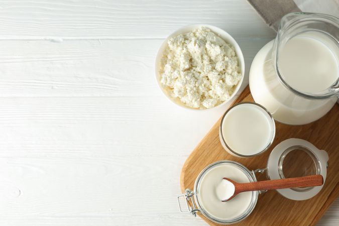 Flat lay. Fresh dairy products, board and towel on plain wooden table