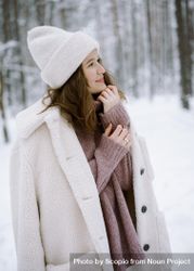 Woman in light knit cap and coat standing on snow covered ground in woods 498qQ5