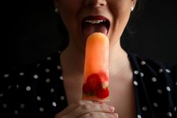 Woman eating fruit popsicle with berries