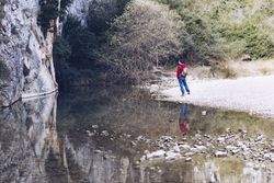 Man on shore near river and stone hill