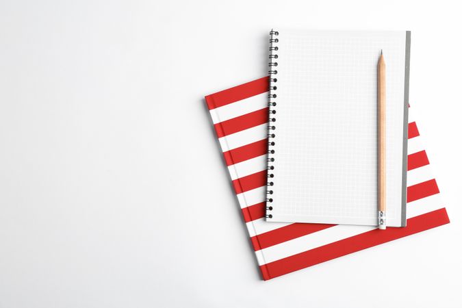 Copybooks and pencil on blank background, top view