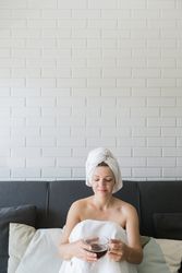 Adult relaxed woman enjoying life while resting on sofa and having hot drink after shower in own cozy apartment