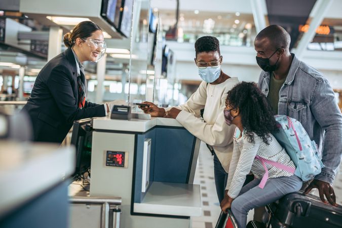 Travelers at check-in counter with airlines staff during pandemic