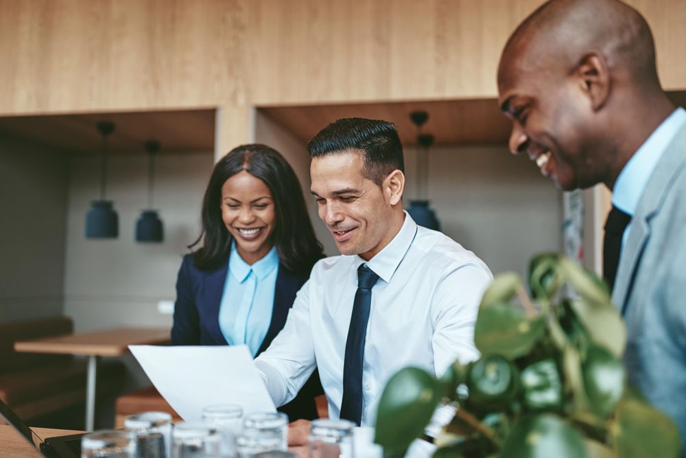 Group of people smiling over a chart in a modern office