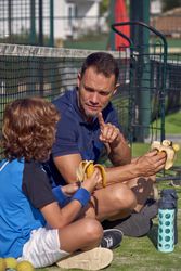 Trainer and boy with bananas sitting on court