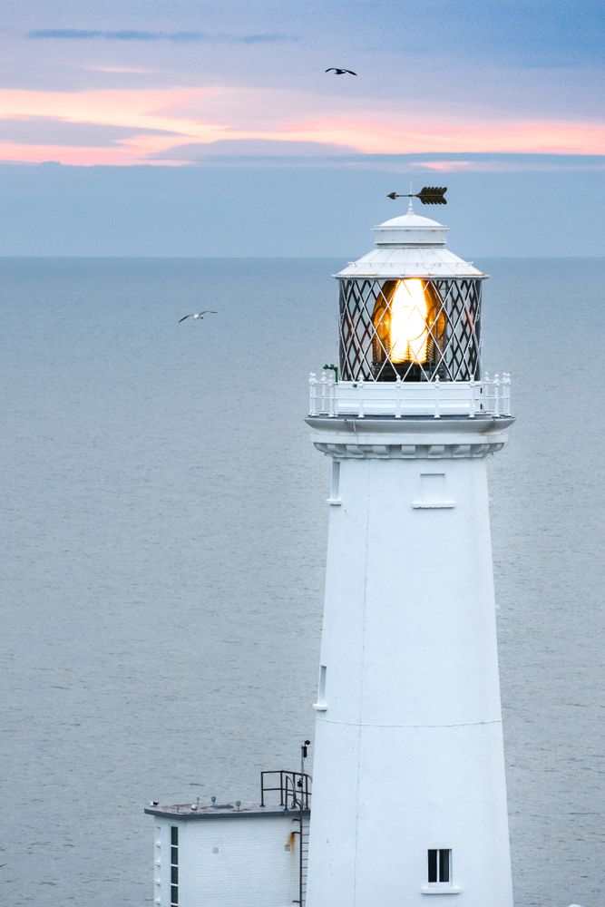 Lighthouse with lighting lamp at sunset