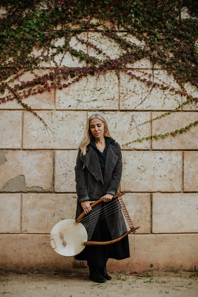 Pensive woman with lyre against brick wall