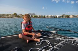 Happy preteen boy sitting on yacht and smiling during cruise in