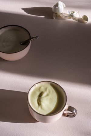 Potato and garlic cream soup in a mug and bowl