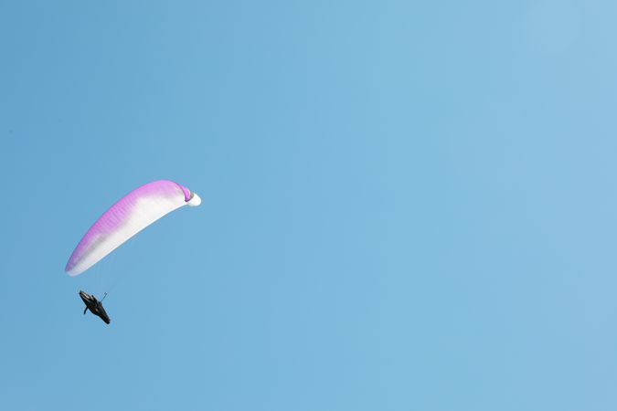 Skydiver with a pink parachute flies across the blue sky