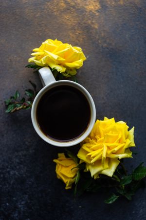 Top view of cup of coffee and yellow roses with copy space
