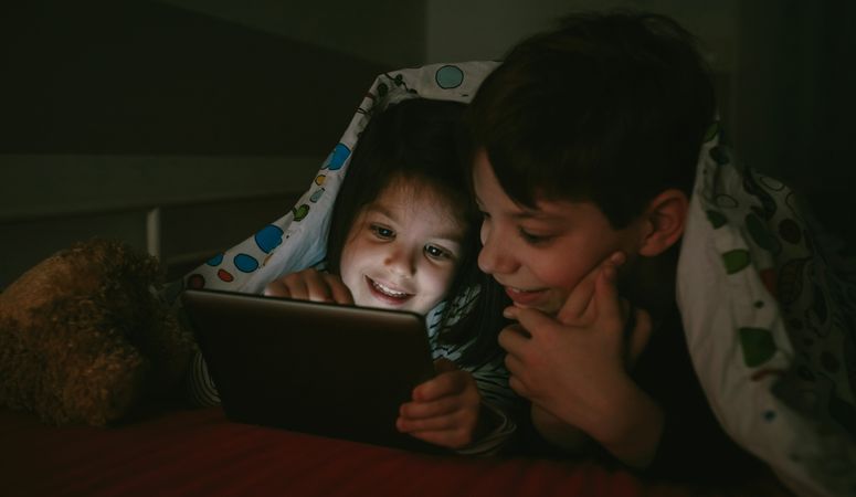Siblings looking at the tablet in the dark